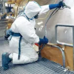 An equipment inspector in protective coverall during an inspection