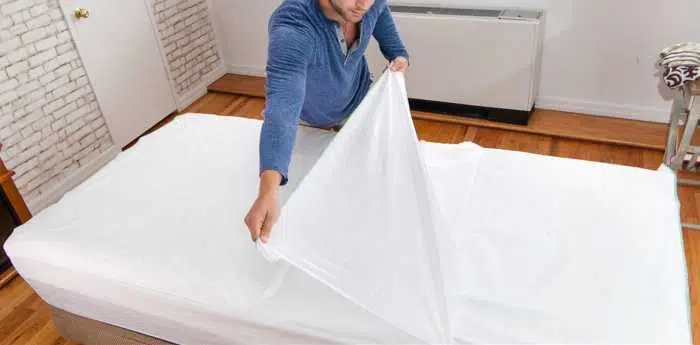 한 남자가 일회용 시트로 침대를 만들고 있습니다.