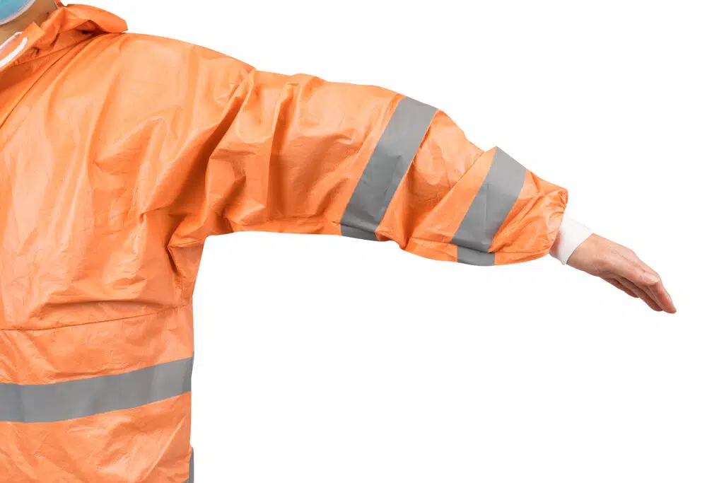 Мужчина в оранжевом защитном костюме со светоотражающими полосами расправляет руки.
