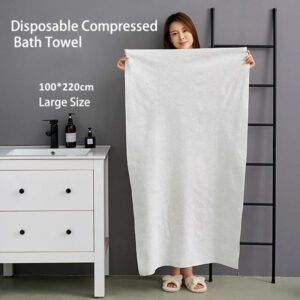 Femme tenant une grande serviette de bain jetable dans une chambre.