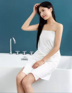 Mujer sentada junto a la bañera, interior de baño moderno.