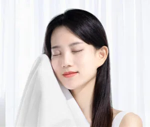 Woman enjoying soft white towel, eyes closed.