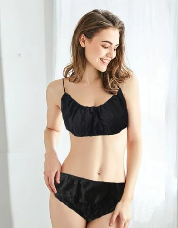 Mulher com um conjunto de lingerie preto de duas peças a sorrir.