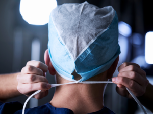 Cirujano atando el cordón de una mascarilla quirúrgica.