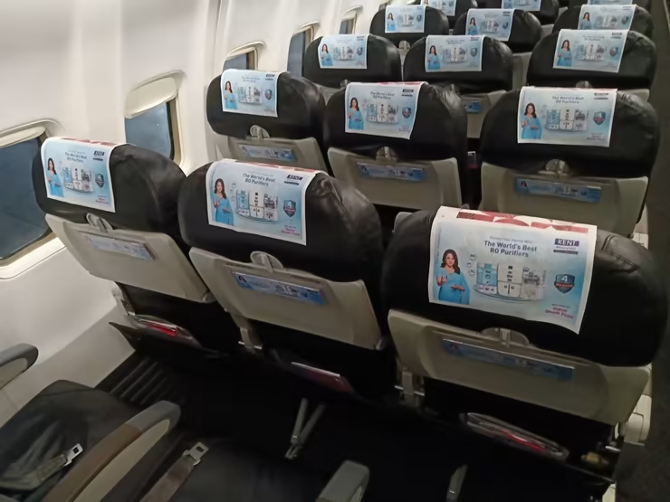 Airplane seats with advertisements on headrests.
