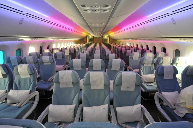 Empty airplane economy class cabin with colorful lighting.
