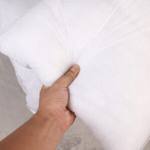 Hand squeezing a soft, white pillow.