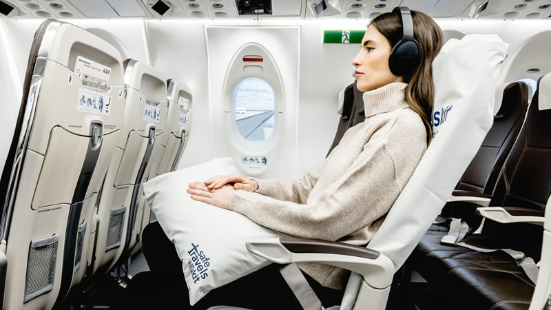 Woman wearing headphones sitting on an airplane.