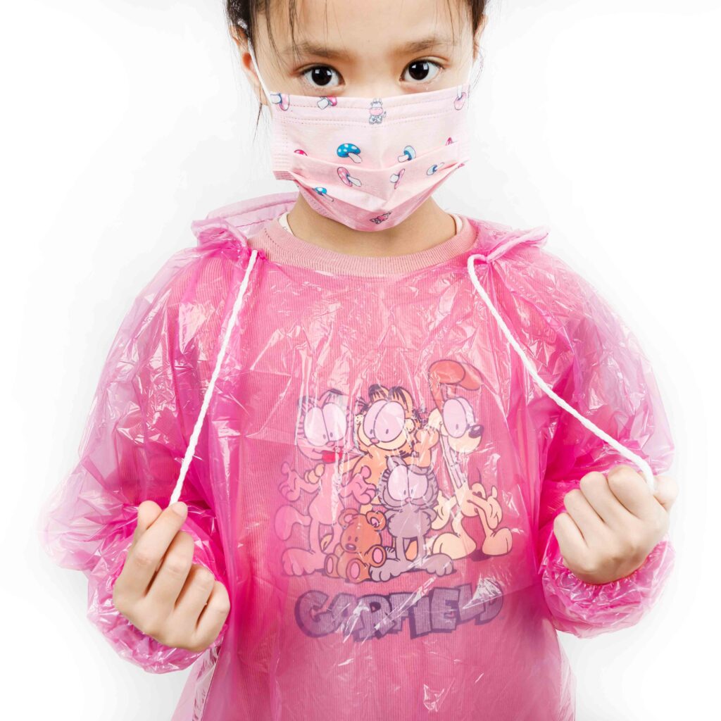 Child wearing pink raincoat and face mask