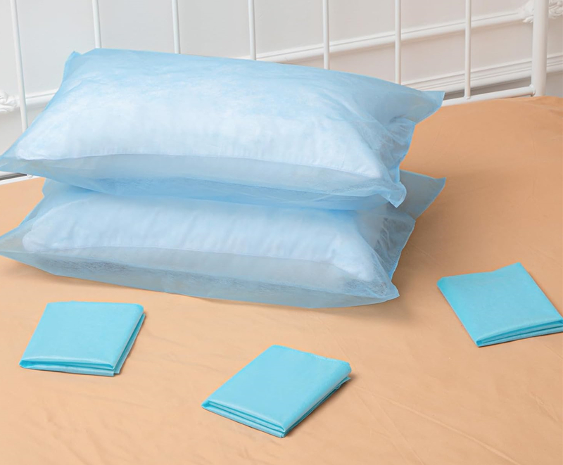 Taies d'oreiller bleues sur couvre-lit beige, draps pliés.