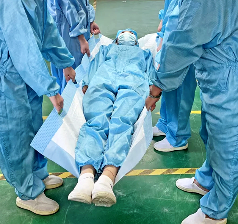 青い服の患者を乗せた担架を運ぶ4人。