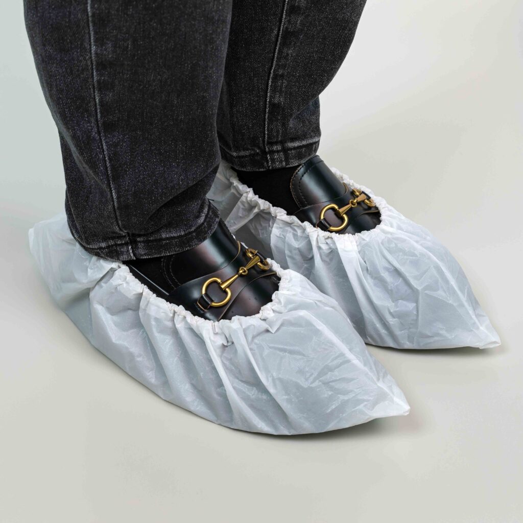 Shoes covered with white shoe protectors on feet.