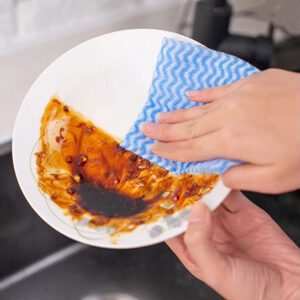 Persona limpiando el plato con una esponja jabonosa.