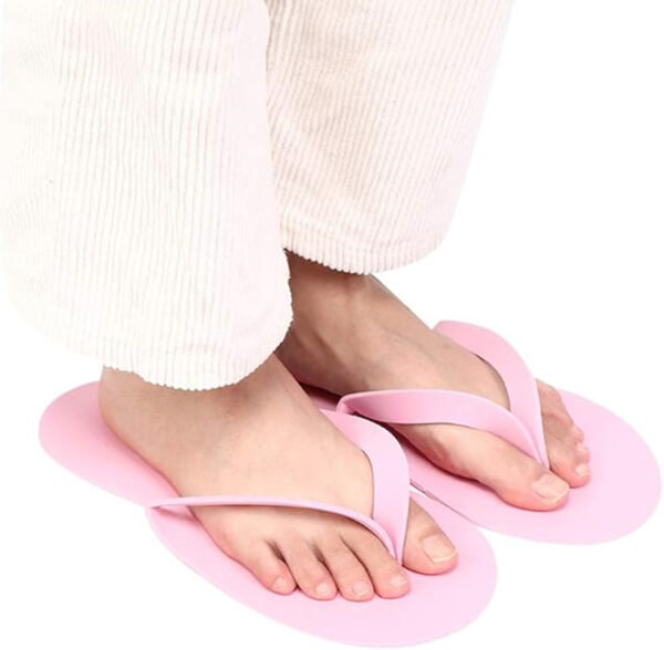 Feet in pink flip-flops and white pants